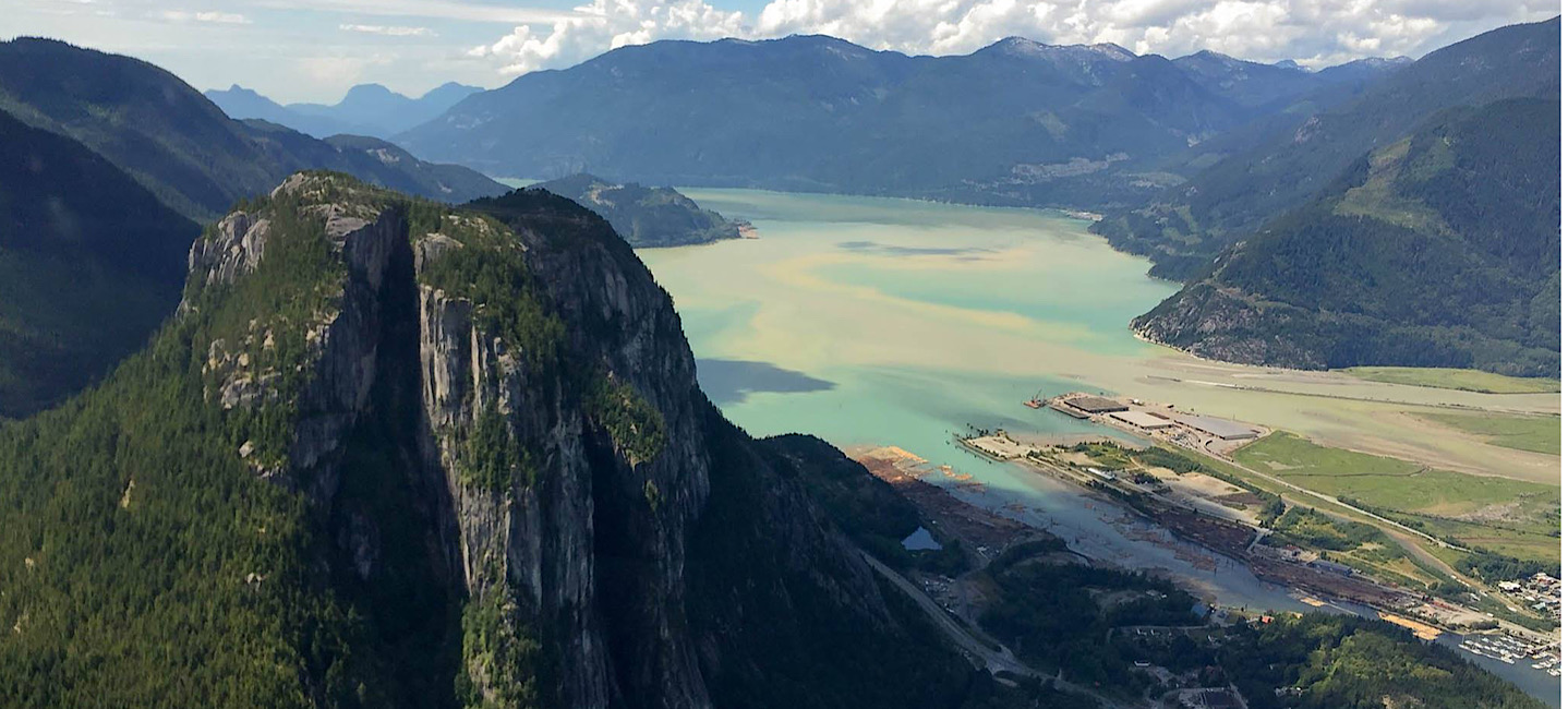 View over Squamish, the Stawamus Chief and over the turquoise waters of the Howe Sound fjord on flight with Sea To Sky Air in the spring