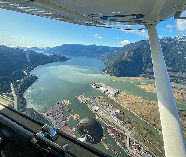 Looking out of the plane window over Squamish, the Squamish Spit, the estuary and Howe Sound Fjord on a summer day