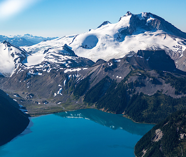 Looking down at Mount Price and Garibaldi Lake shimmering a vibrant, deep blue in the summer light